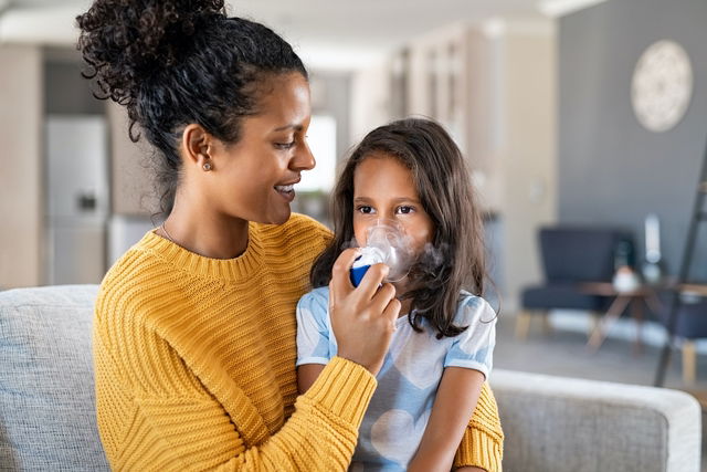 Tratamiento de la tos por inhalación. bebé con un nebulizador en sus manos,  máscara de respiración en su rostro.