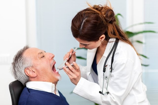 Médica examinando a cavidade oral de um paciente