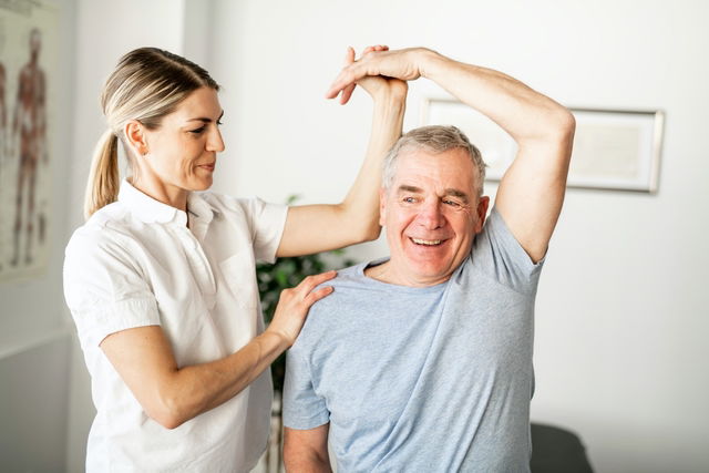 Fisioterapeuta fazendo exercício com o braço de um senhor idoso