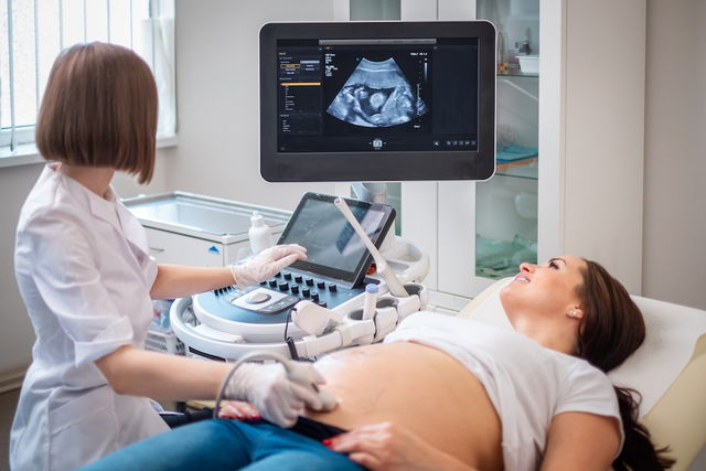 Obstetra fazendo ultrassom na gestante para localizar o cordão umbilical