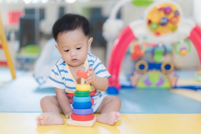 Bebê com 9 meses montando uma pequena torre com um brinquedo