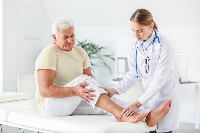 Médico dermatologista examinando a pele da perna de um homem