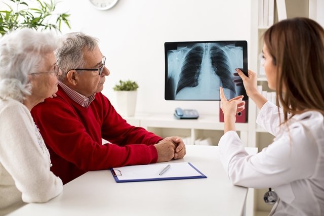 Doctora en una consulta mostrando una radiografía de tórax a un paciente