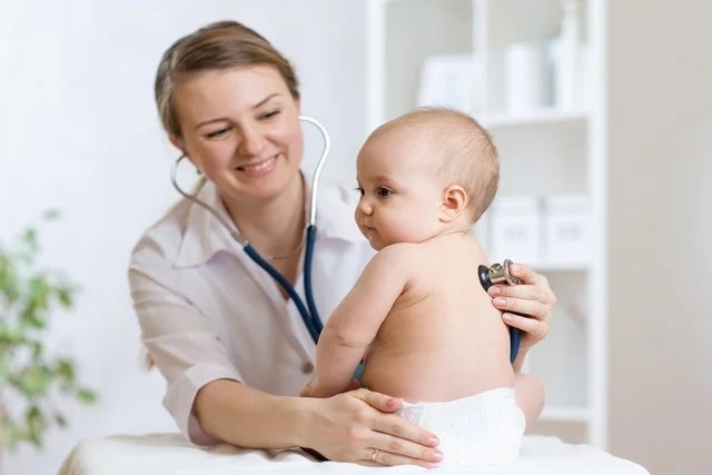 Pediatra esuchando la respiración del bebé con el estetocopio
