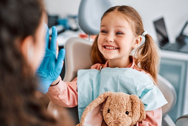 Dentista avaliando dentinhos de uma criança