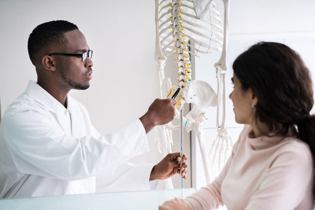 Médico explicando sobre a anatomia da coluna vertebral para uma paciente no consultório