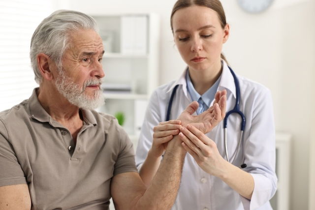 Reumatóloga verificando la mano y brazo de un señor mayor