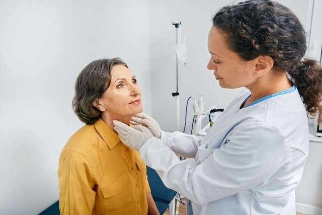 Endocrinóloga examinando el cuello de una mujer