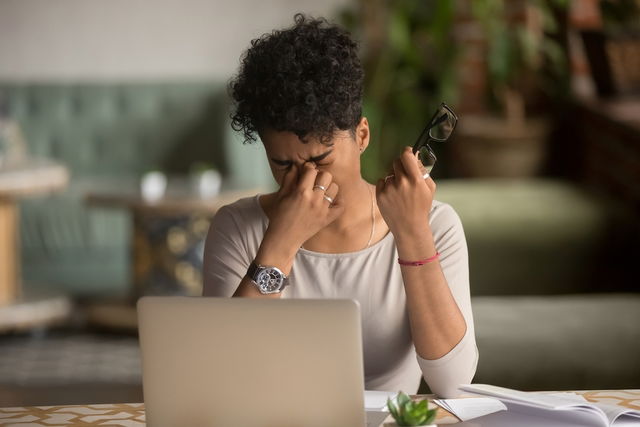 femme qui se touche les yeux et qui se plaint de douleur