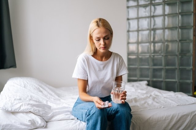 Mujer sentada en la cama con una pastilla de doxilamina