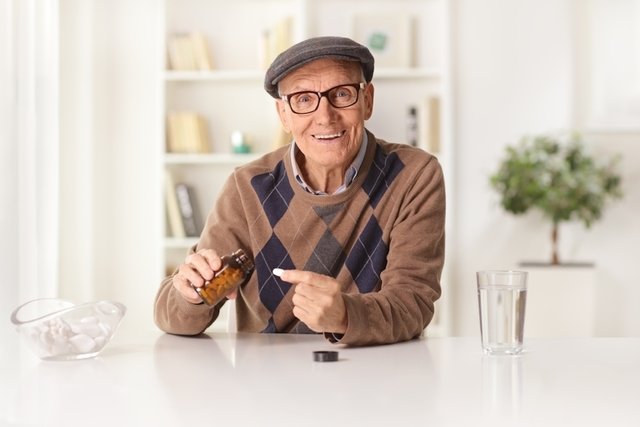 Persona mayor con una tableta de atosvastatina