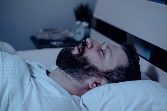 Hombre durmiendo en la cama mientras ronca