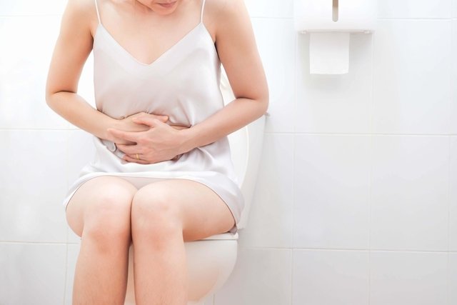 Mujer con dolor de panza, sentada en la sanita