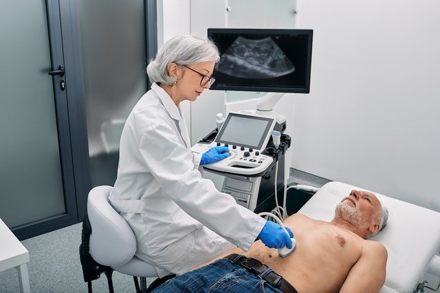 Uma médica realizando um exame de ultrassom abdominal em um paciente