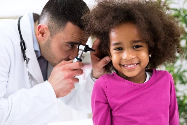 Pediatra examinando o ouvido de uma criança sorridente