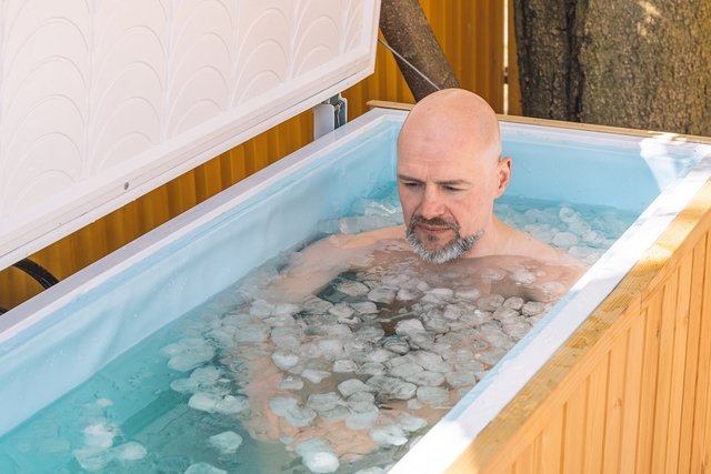Hombre en una bañera sumergida en agua helada. 
