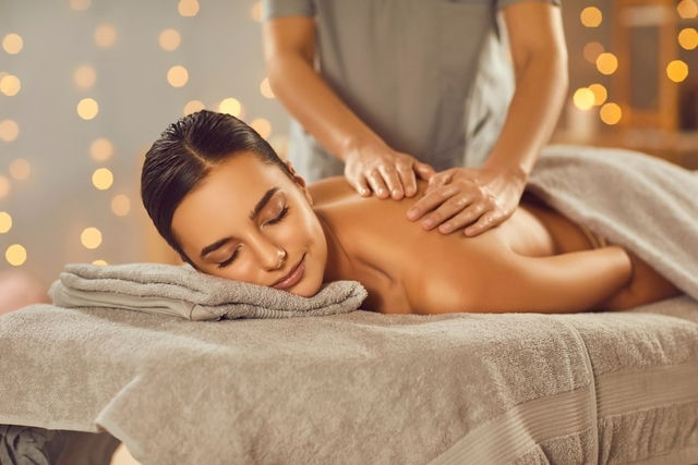 Mujer acostada en una camilla recibiendo un masaje relajante