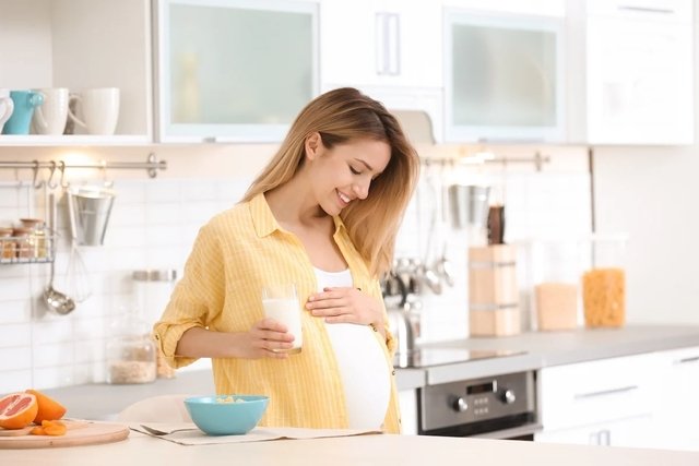 Mujer embarazada con un vaso de leche, un alimento que aporta magnesio