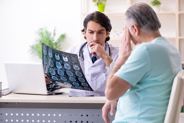 Médico analisando o exame de ressonância magnética do crânio de um paciente durante a consulta