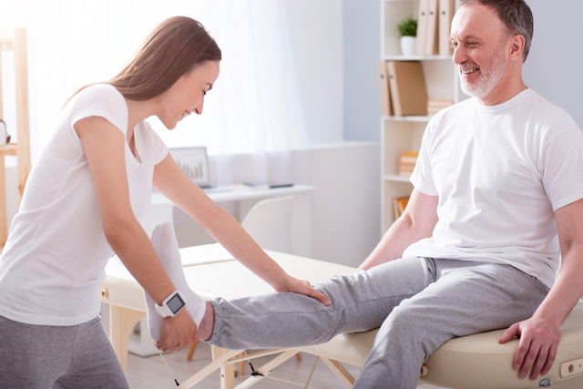 Fisioterapeuta fazendo exercício com a perna de um senhor idoso