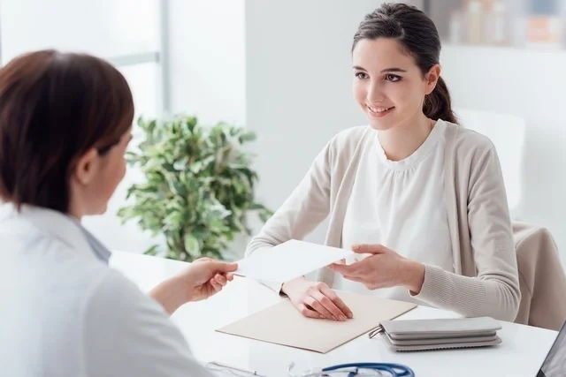 Mujer jóven en un consultorio recibiendo una receta médica de la ginecóloga